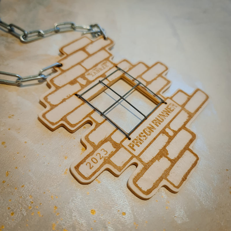 Sklejkowy medal Prison Runner z motywem muru i napisem "Prison Runner"